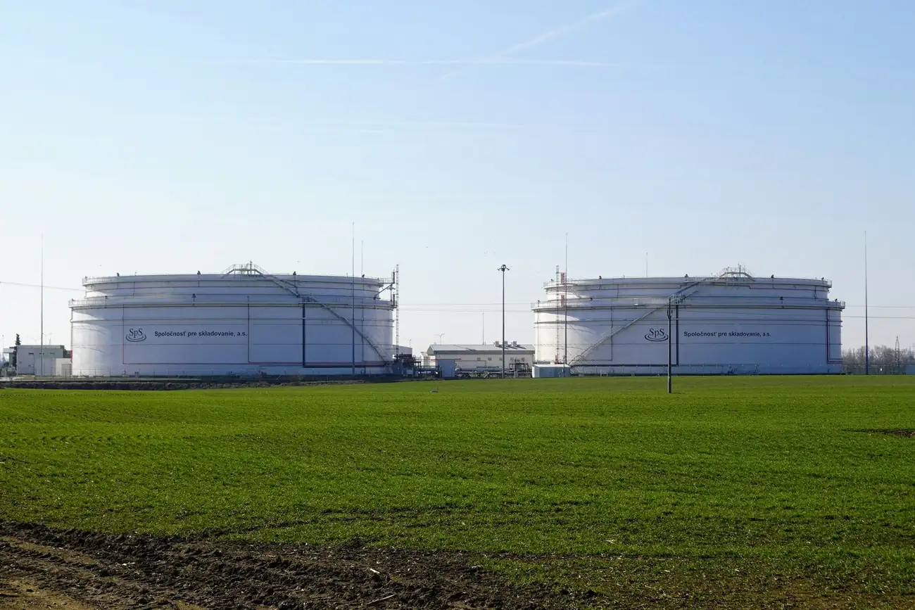 Large white fuel storage tanks beside a green field